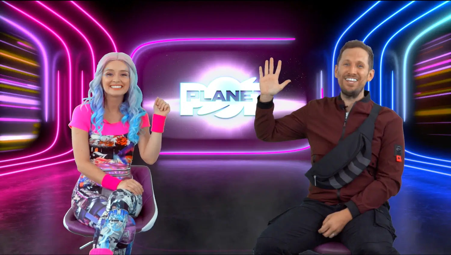 Two people sitting on a set with colorful neon lights and a 'Planet' logo in the background.